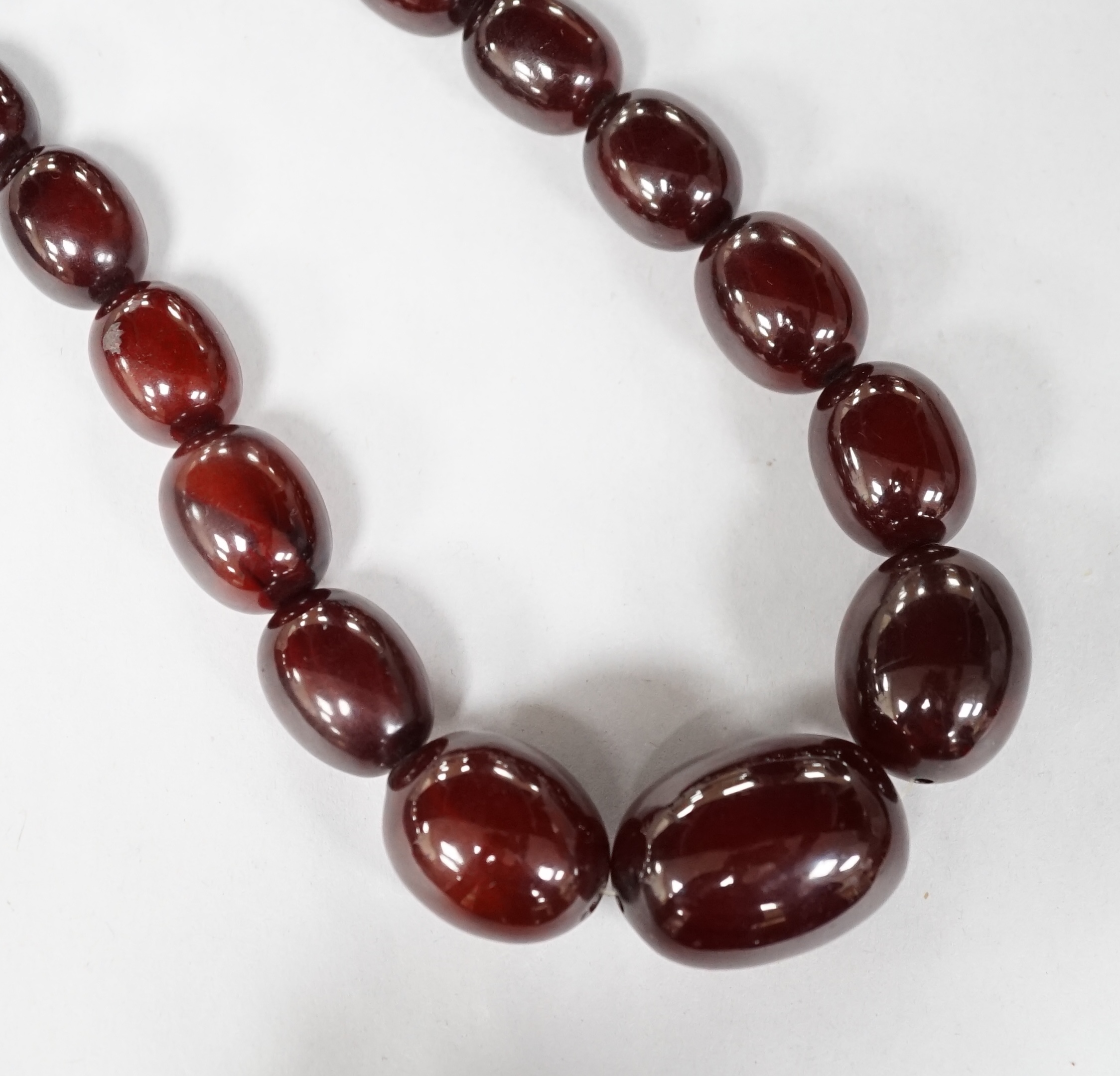 A single strand graduated simulated cherry amber oval bead necklace, 98cm, gross weight 140 grams. Condition - fair to good